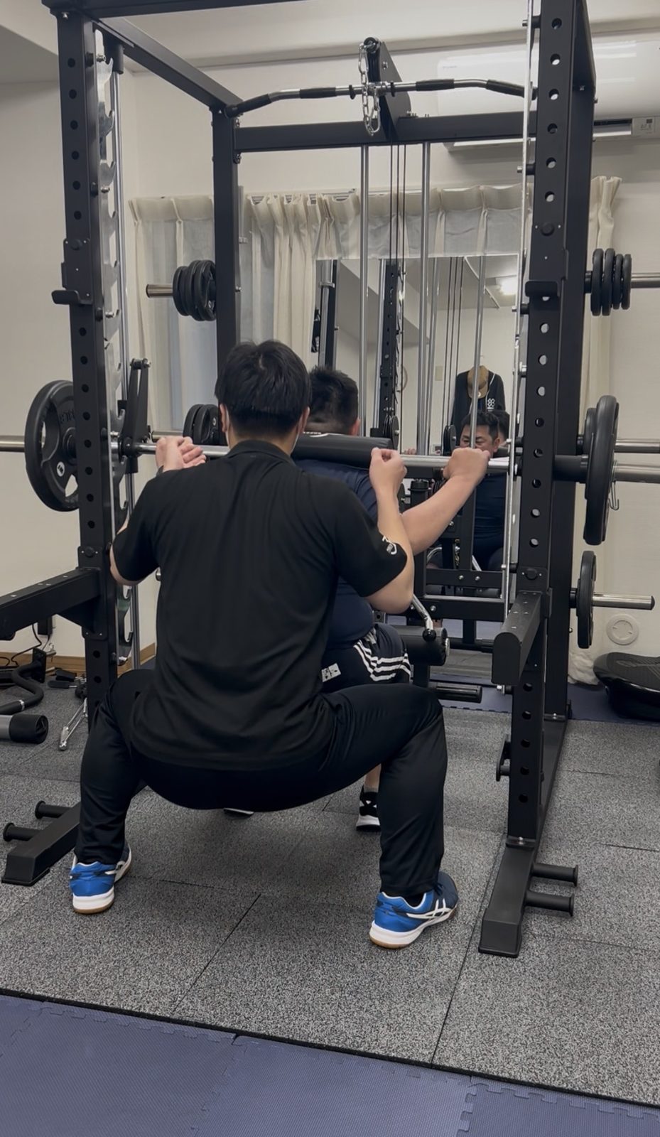 トレーナーがスクワットを補助している様子